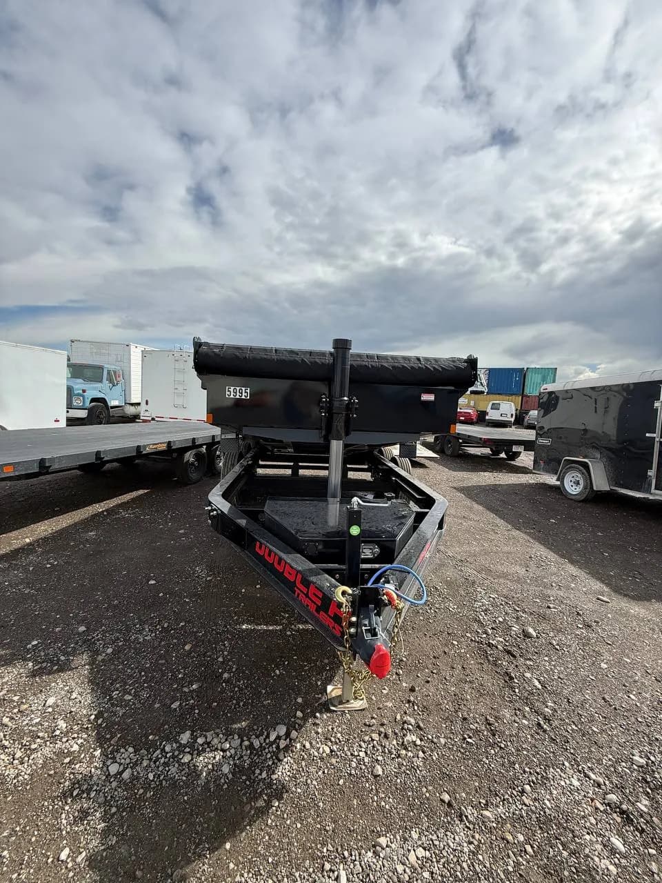 Rolled mesh tarp and its crank handle across the front of the dump trailer box