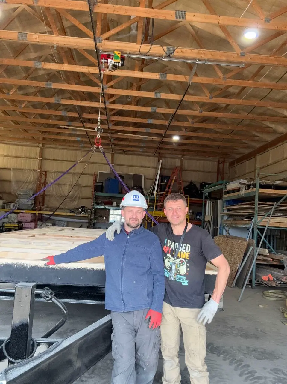 Two Excel Trailers builders standing beside a new office trailer floor deck in the Calgary shop