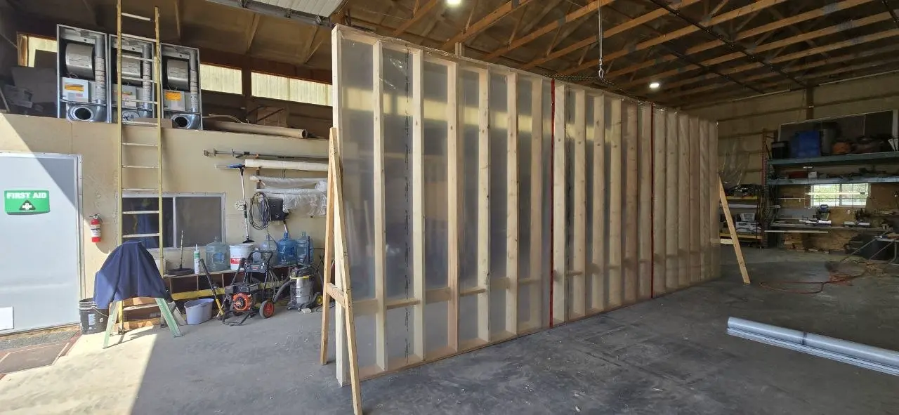 Office trailer wall panel with polyethylene vapour barrier stapled over the studs