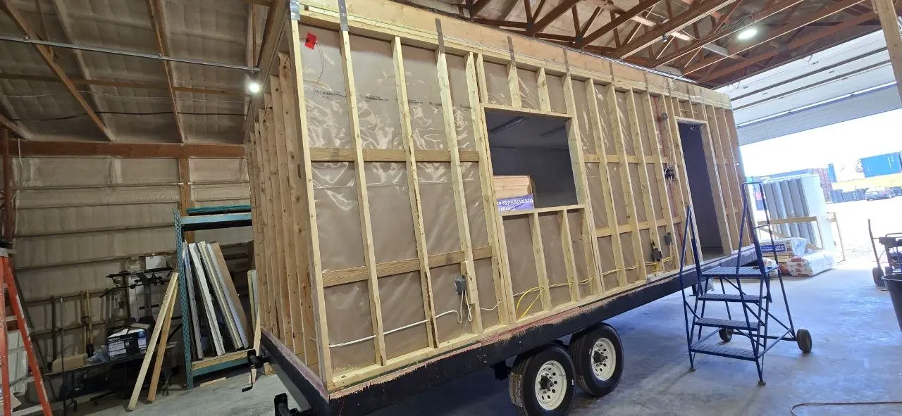 Office trailer wall framing with window openings, door and roughed-in wiring on the chassis