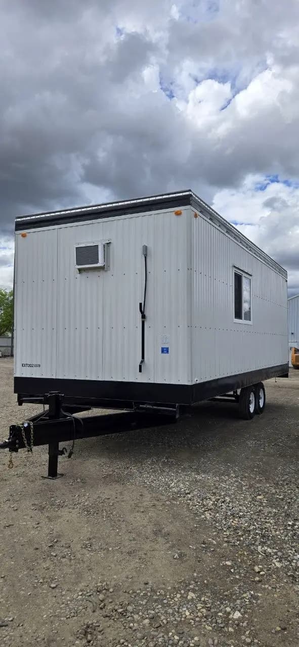 Side view of a finished new office trailer with wall-mounted air conditioner and tandem axles