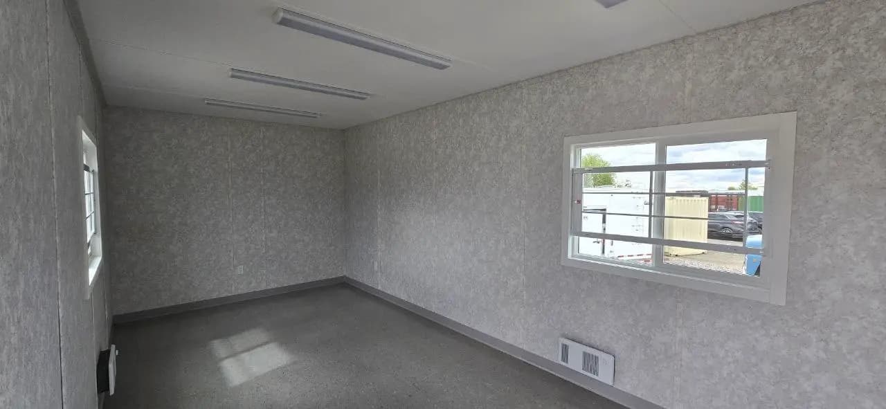 Interior corner of a finished office trailer showing window, floor vent and LED strip lighting